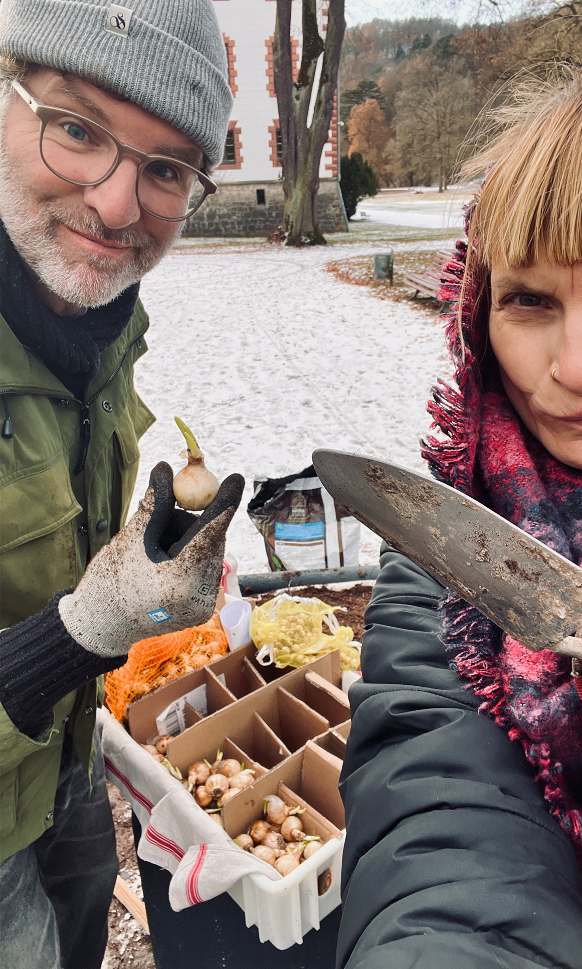 Zwei Vereinsmitglieder mit Blumenzwiebeln und Pflanzkelle im Schnee